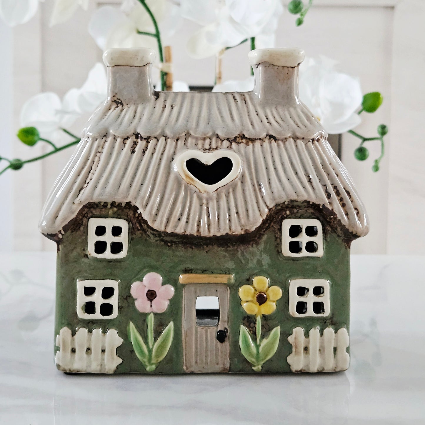 stoneware green house-shaped tea light holder with a heart window and floral decorations