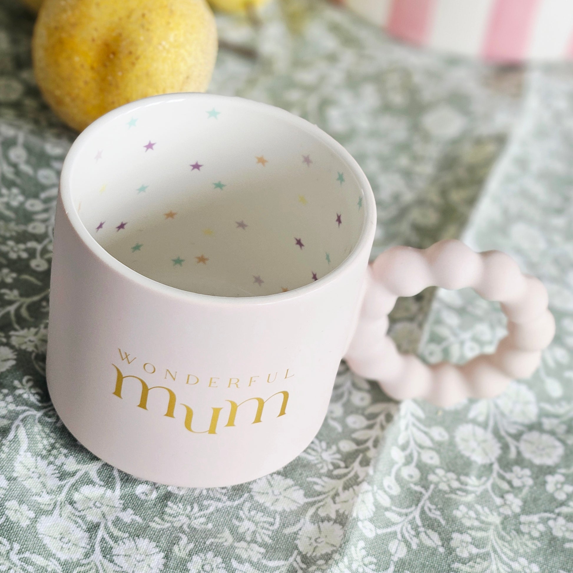 White mug with 'Wonderful mum' text and multi coloured stars inside with confetti design and bobble handle
