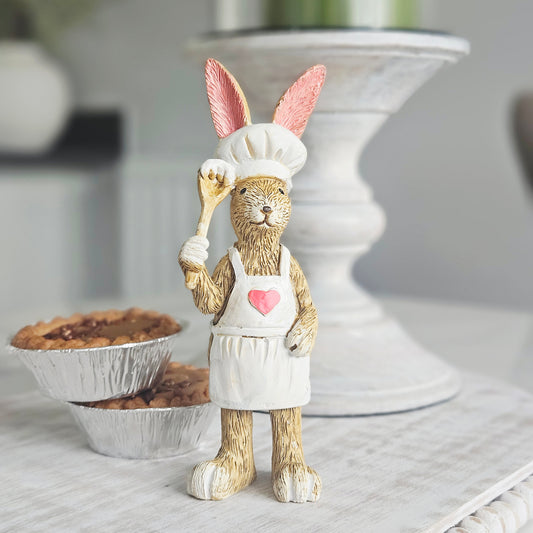 A decorative jasper rabbit figurine dressed as a chef, wearing a white hat and apron with pink inner ears and a pink heart on the chest