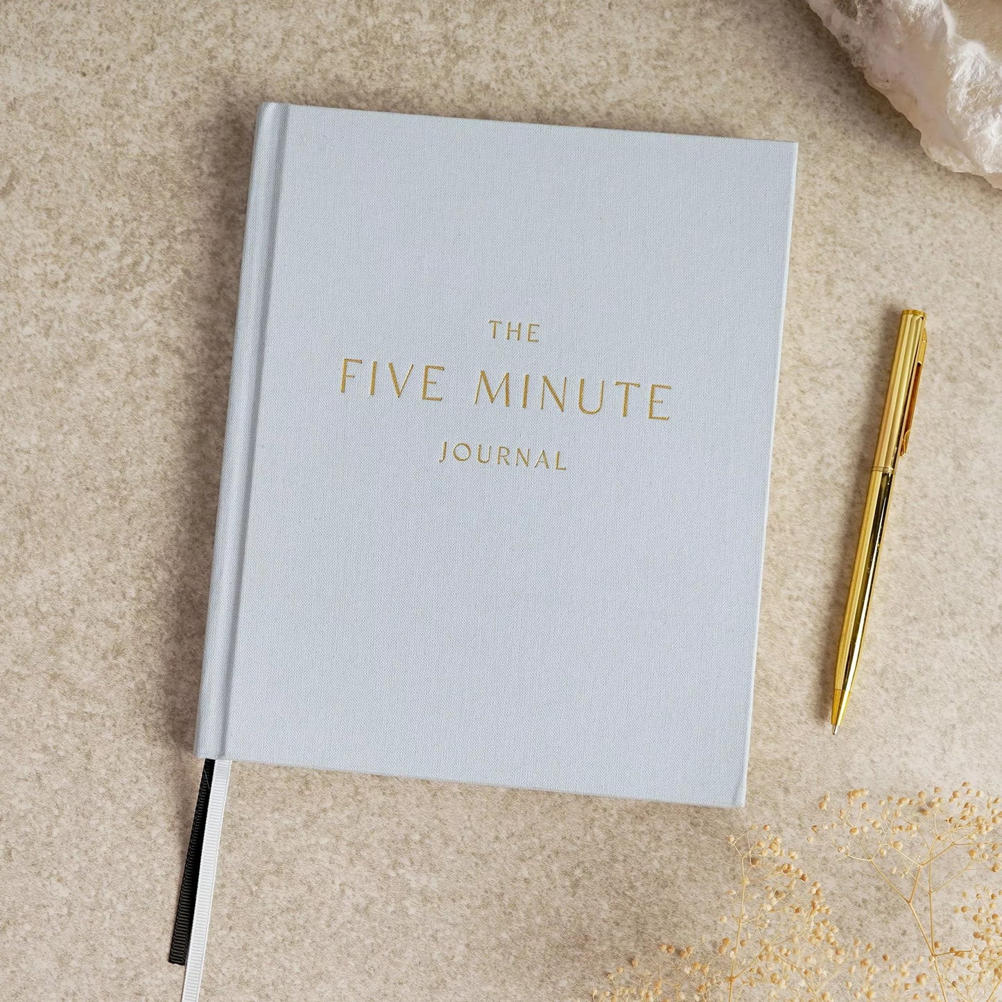 Light blue journal titled 'The Five Minute Journal' with a gold pen 