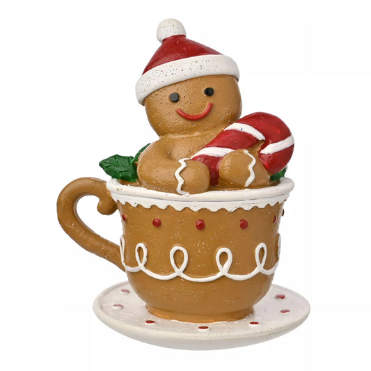 Decorative gingerbread man in a mug with a candy cane and santa hat