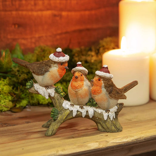 Decorative figurine of three robins wearing Santa hats on a branch 