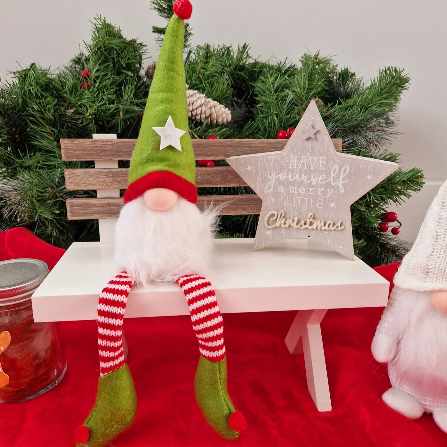 Sitting elf gonk green and red hat, striped dangly legs and green booties with red pom poms.